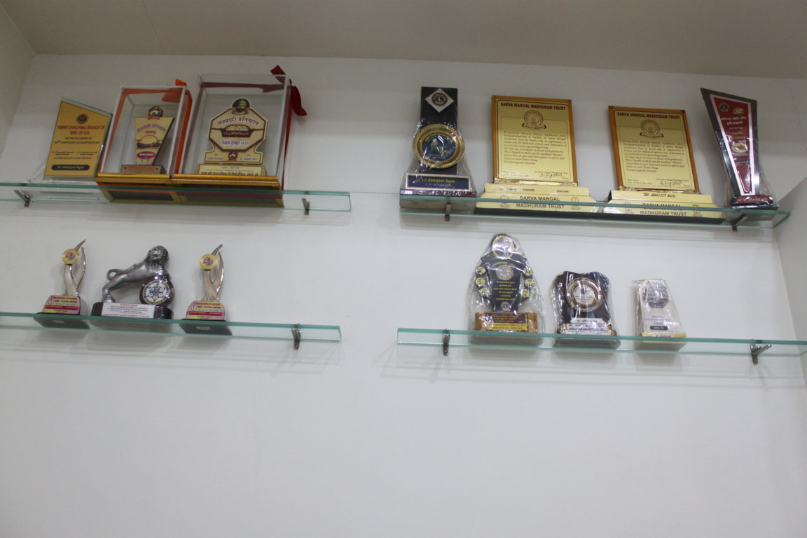 Glass display shelves at Insight Institute holding institutional accolades, medical society awards and trust recognition trophies